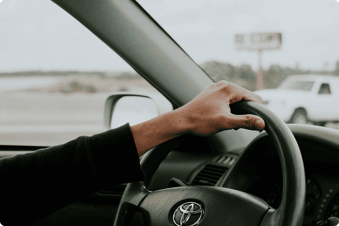 Image of a person holding the steering wheel of a car.